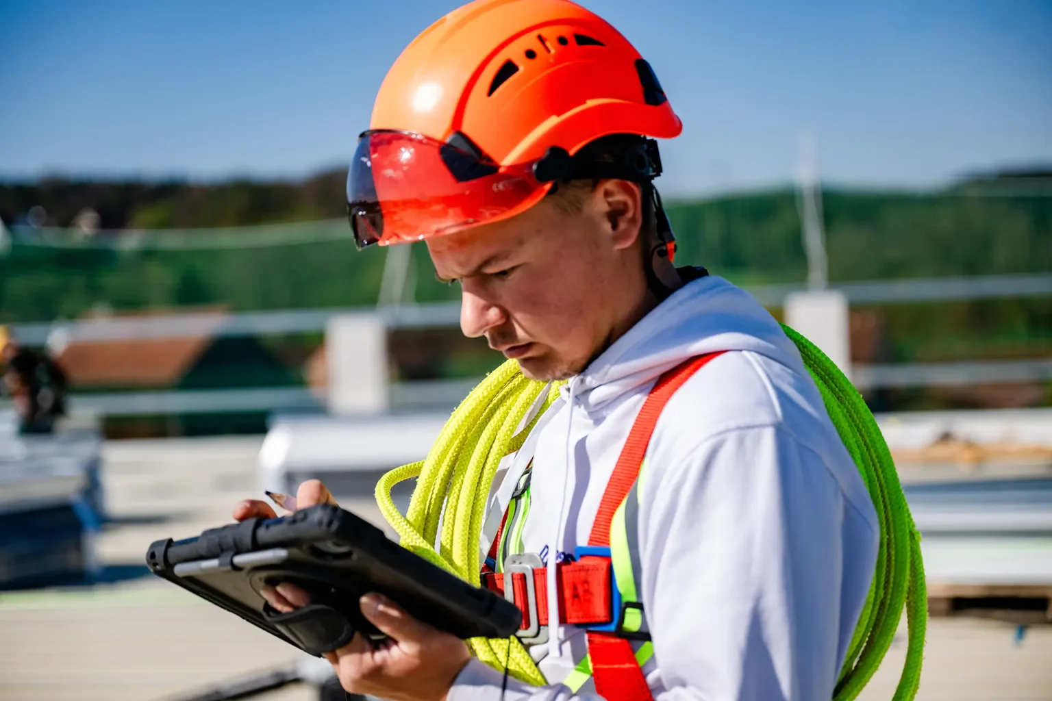 Bauleiter mit Helm und Tablet auf einer Baustelle.